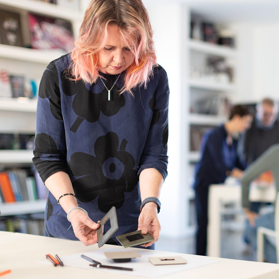 The Group Vice President, Art &amp; Design examines different Light Now cover plates at a table in a brightly lit studio space.