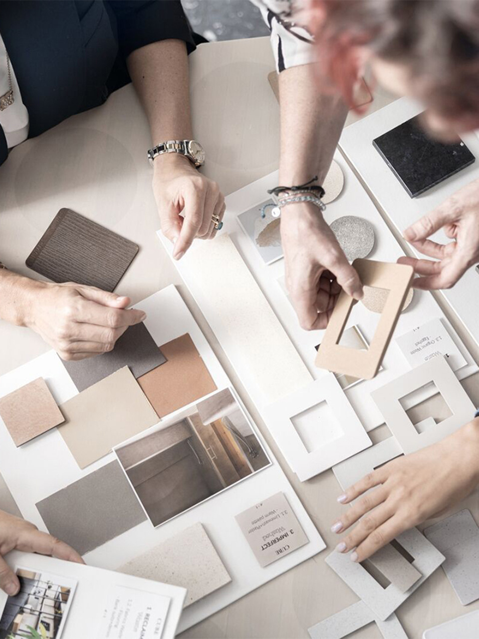 Four people arranging material and color samples on a table, for an interior design project.