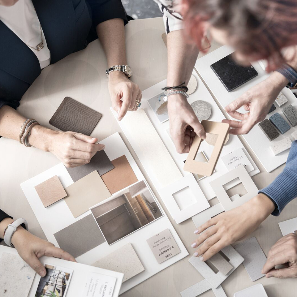 Four people arranging material and color samples on a table, for an interior design project.