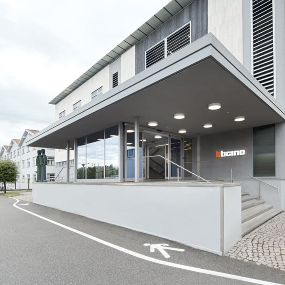 Modern building entrance with ramp, glass walls, and Bticino headquarter sign on the facade in Varese.