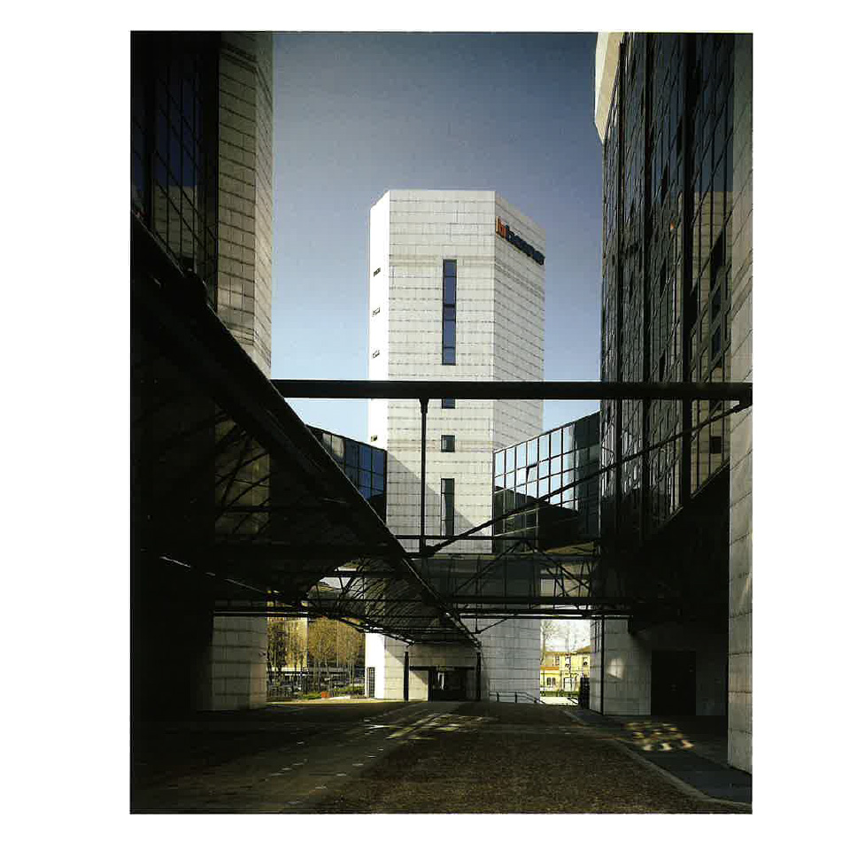 White high-rise once used as Bticino headquarter in Milano, with glass skybridges linking modern office structures.