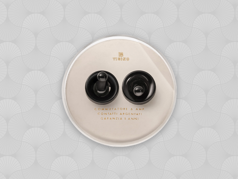 BTicino Ticino round electrical switch with two black toggles, on a patterned background.