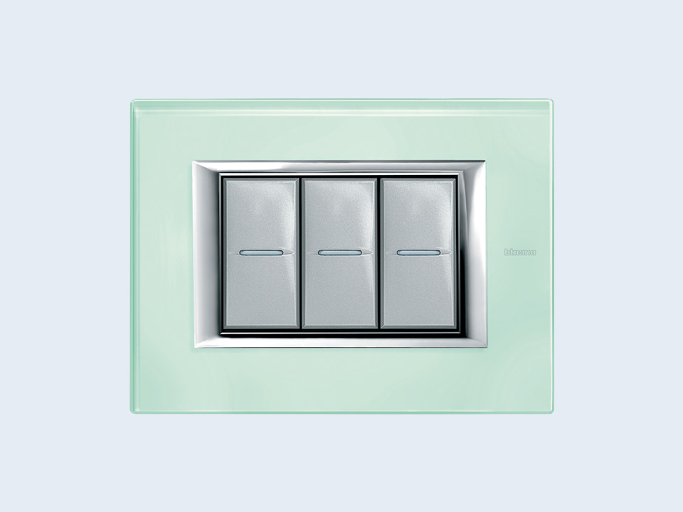 BTicino Axolute 3-module aquamarine cover plate, on a light blue background.