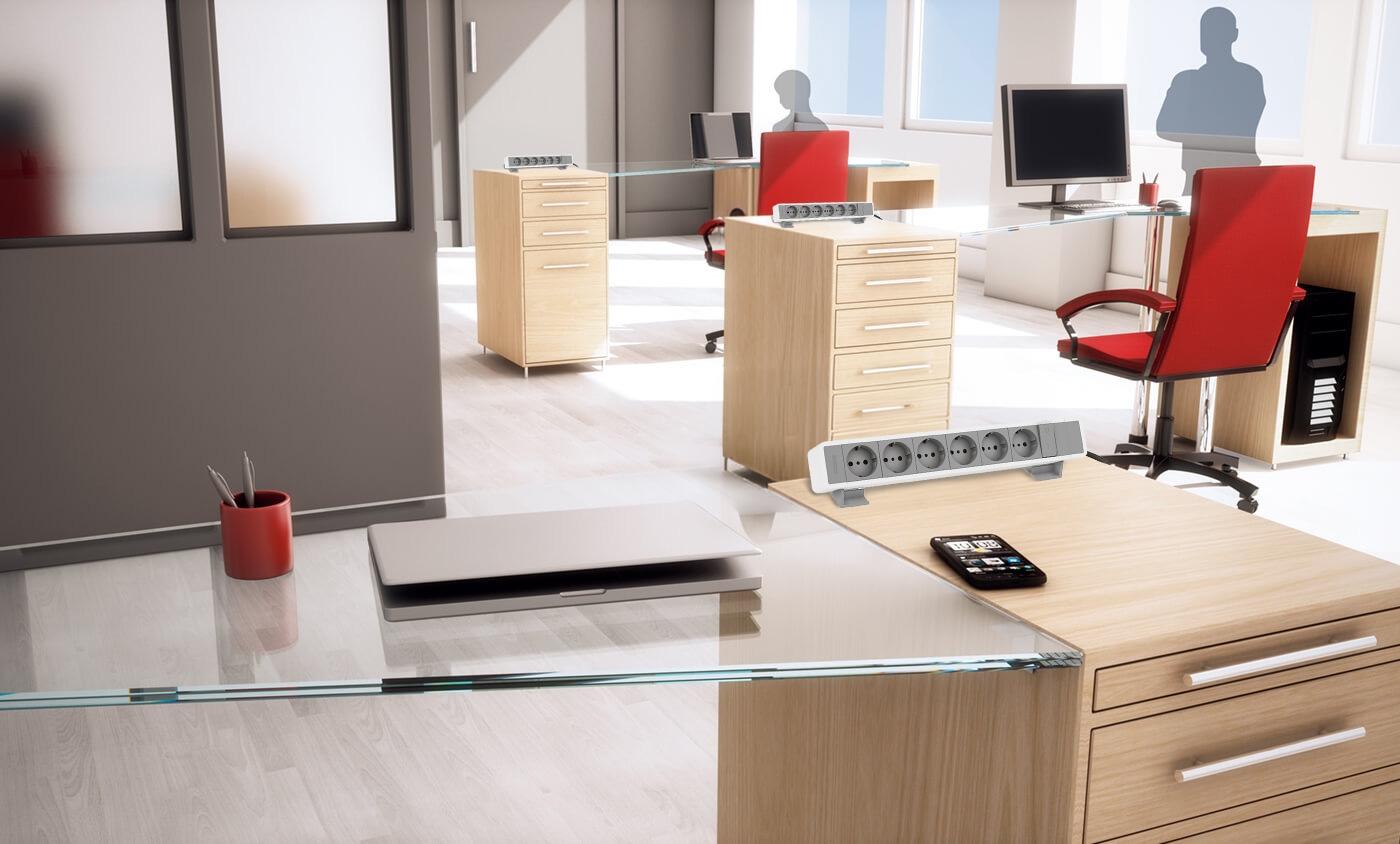 A modern office with glass desks, red chairs, computers, smartphones and BTicino 1508664WG power strips.