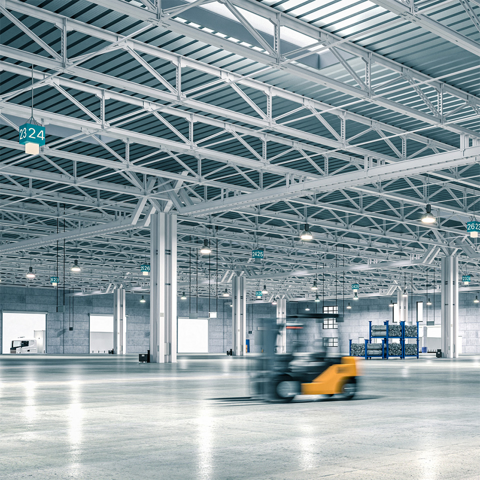 A blurred forklift moves through a spacious, modern warehouse with high ceilings and steel beams.