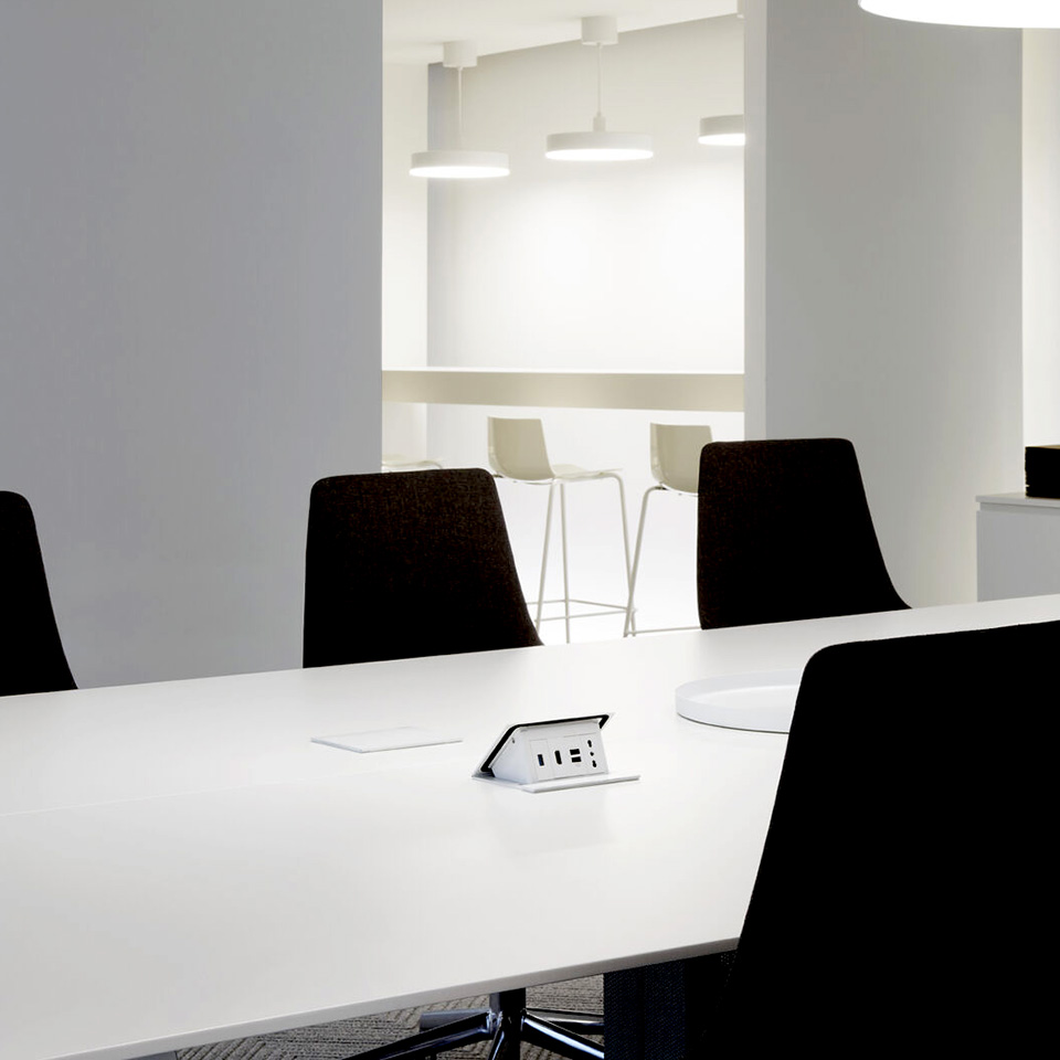 Modern conference room with black chairs and a white desk with a POP-UP retractable turret.