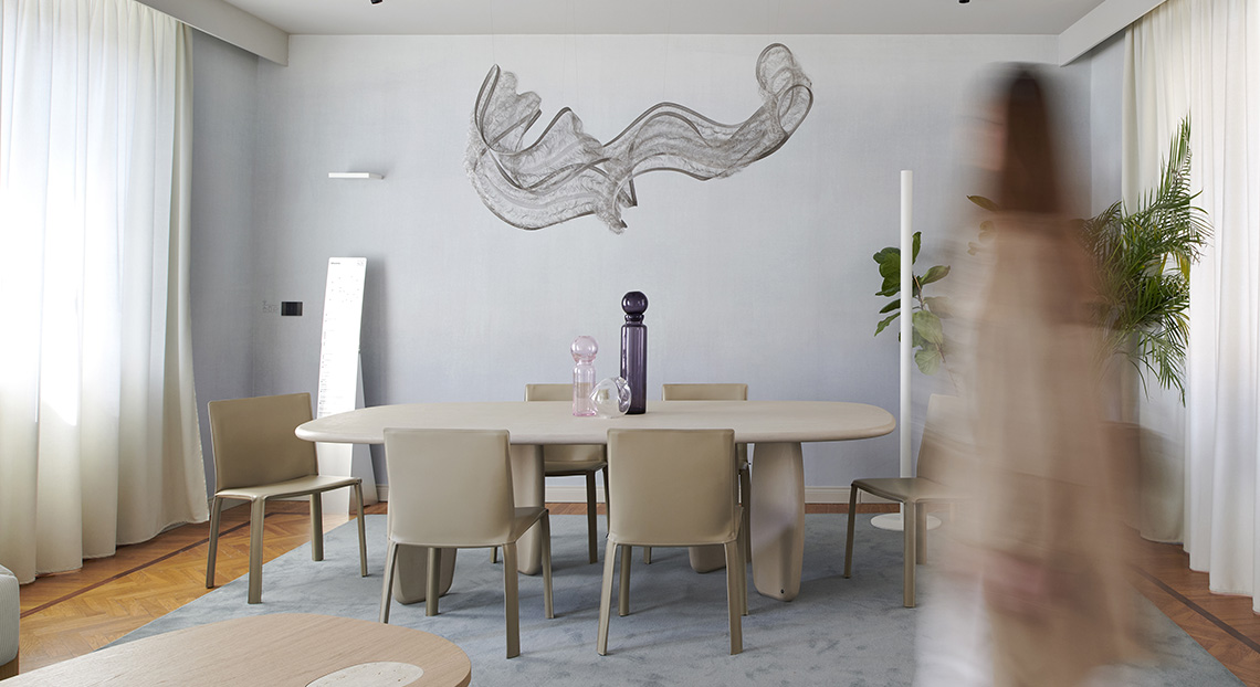 Living room of BTicino smart apartment with a wooden table, beige chairs, and a design chandelier at Fuorisalone 2026.