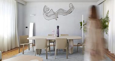 Living room of BTicino smart apartment with a wooden table, beige chairs, and a design chandelier at Fuorisalone 2026.